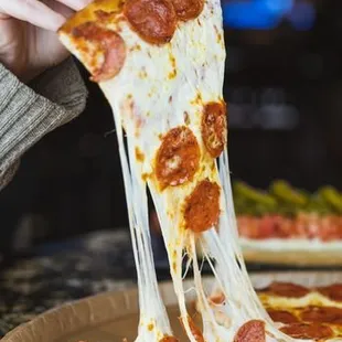 a woman eating a slice of pepperoni pizza