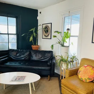 a living room with a black leather couch and a white coffee table