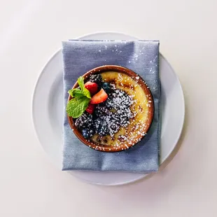 Indulge in our Vanilla Crème Brulee, garnished with fresh berries.