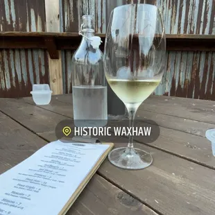 a glass of wine and a menu on a wooden table