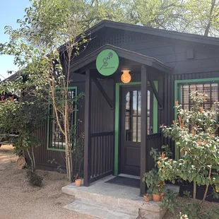 a small black building with green trim