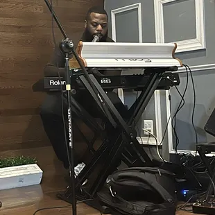 a man sitting at a keyboard in front of a microphone