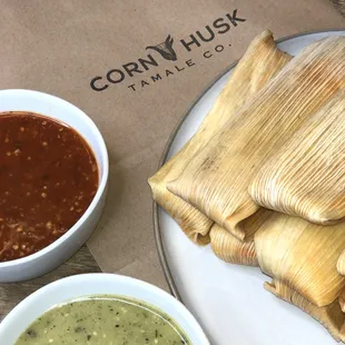a bowl of salsa and a plate of tamales