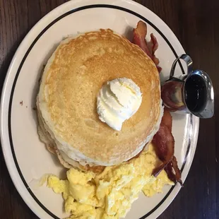 a stack of pancakes with bacon and eggs