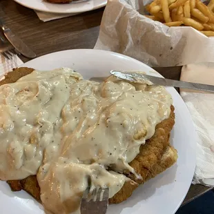 a plate of fried chicken with gravy and french fries