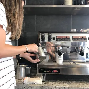 a woman preparing a cup of coffee