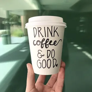 a hand holding a coffee cup that says drink coffee and do good