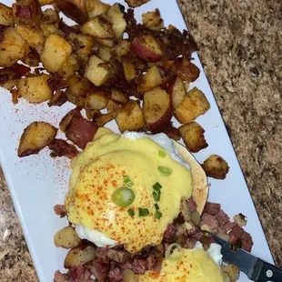 a plate of eggs benedict and potatoes