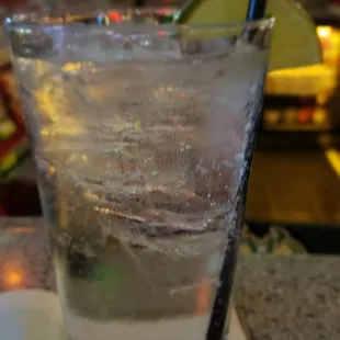 a glass of water with ice and a lime slice