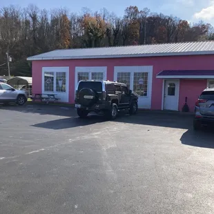 two cars parked in front of a pink building