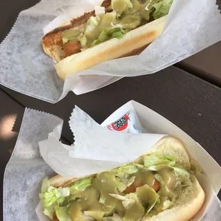 two hotdogs with lettuce and pickles
