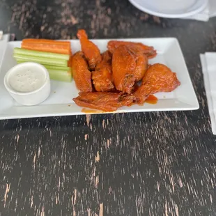 a plate of buffalo wings and celery sticks