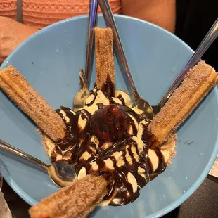 a blue bowl of ice cream, chocolate sauce, and bananas