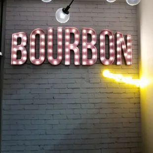 a brick wall with a neon sign that reads bourbon