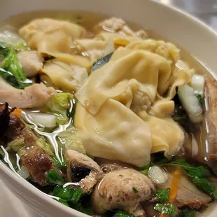 a bowl of soup with dumplings and vegetables
