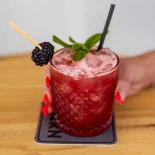 a hand holding a blackberry mojita