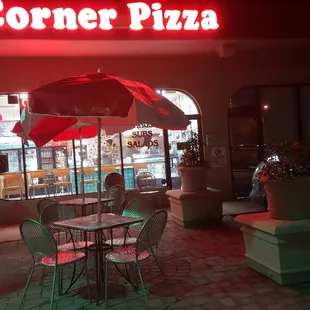 a woman sitting at a table under an umbrella