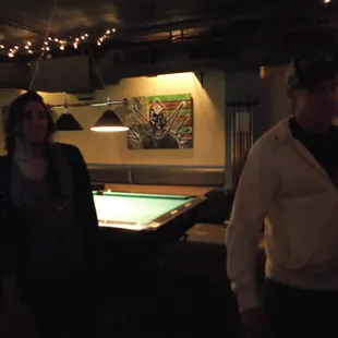 a man and a woman standing in front of a pool table