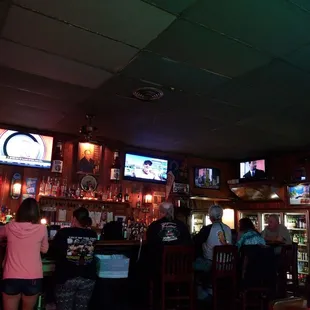 people sitting at bar watching televisions
