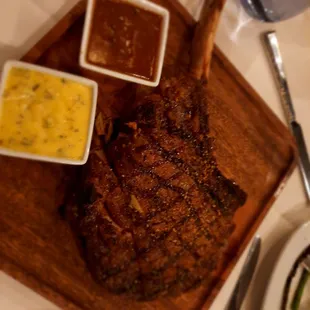 a steak on a cutting board with sauces