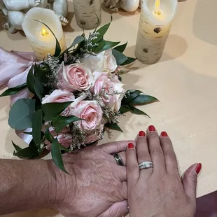 This is my bouquet next to our hands with our rings on our fingers after the wedding ceremony