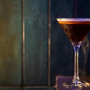a dark drink in a martini glass