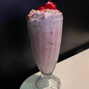 a strawberry milkshake with whipped cream and cherries