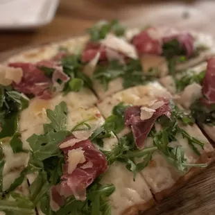 a flatbread pizza with prosciutto and arugula