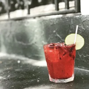 a red drink with a lime slice