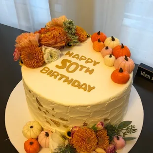 a cake decorated with flowers and pumpkins
