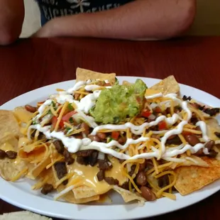 Macho nachos. Pinto beans, carne asada, crema, shredded cheese, nacho cheese, pico de gallo, guac, and bits of fresh jalapeno.