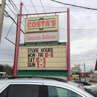 a store hours sign on top of a car