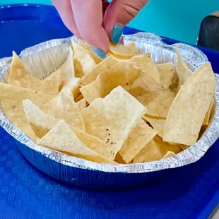 a person dipping tortilla into a bowl of tortillas