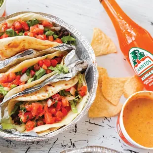a plate of tacos with salsa and tortillas