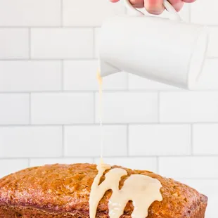 a person pouring icing onto a loaf of cake