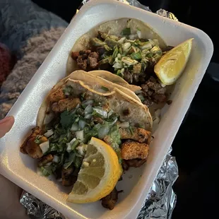a person holding a tray of tacos