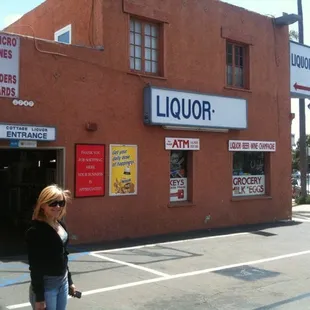 a woman walking in front of a liquor store