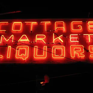 a neon sign that reads cottage market liquors