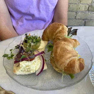 a croissant sandwich on a glass plate