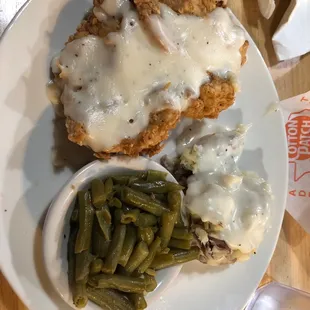 a plate of fried chicken with gravy and green beans