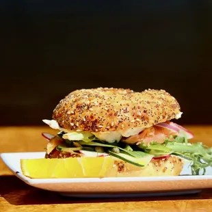 Smoked salmon on herbed cream cheese radish and cucumber fresh dill on a toasted everything bagel