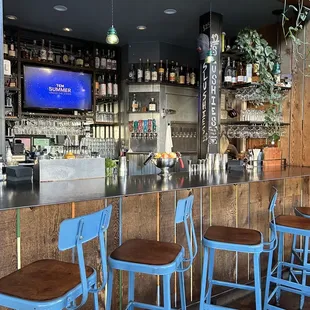 a bar with blue stools and a flat screen tv