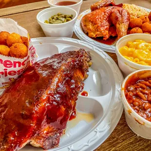 a plate of ribs, beans, and corn