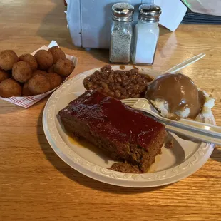 Meatloaf, baked beans, mashed potatoes with brown gravy, and hush puppies.