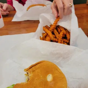 a woman sitting at a table with a sandwich and fries