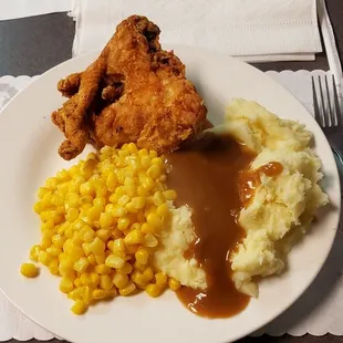 Delicious fried chicken, mashed potatoes with brown gravy and corn.