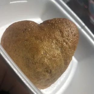 a heart shaped piece of bread in a styrofoam container