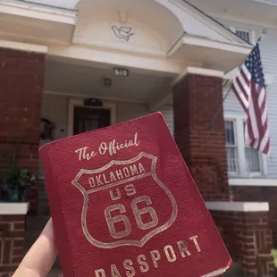 a hand holding a passport in front of a house