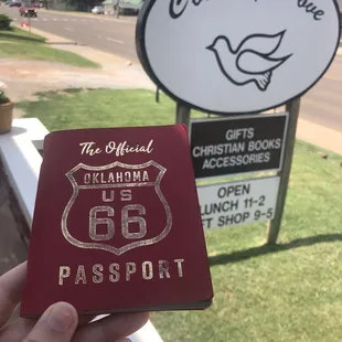 a hand holding a passport in front of a sign