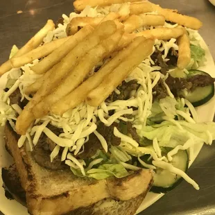 a steak sandwich with fries and lettuce